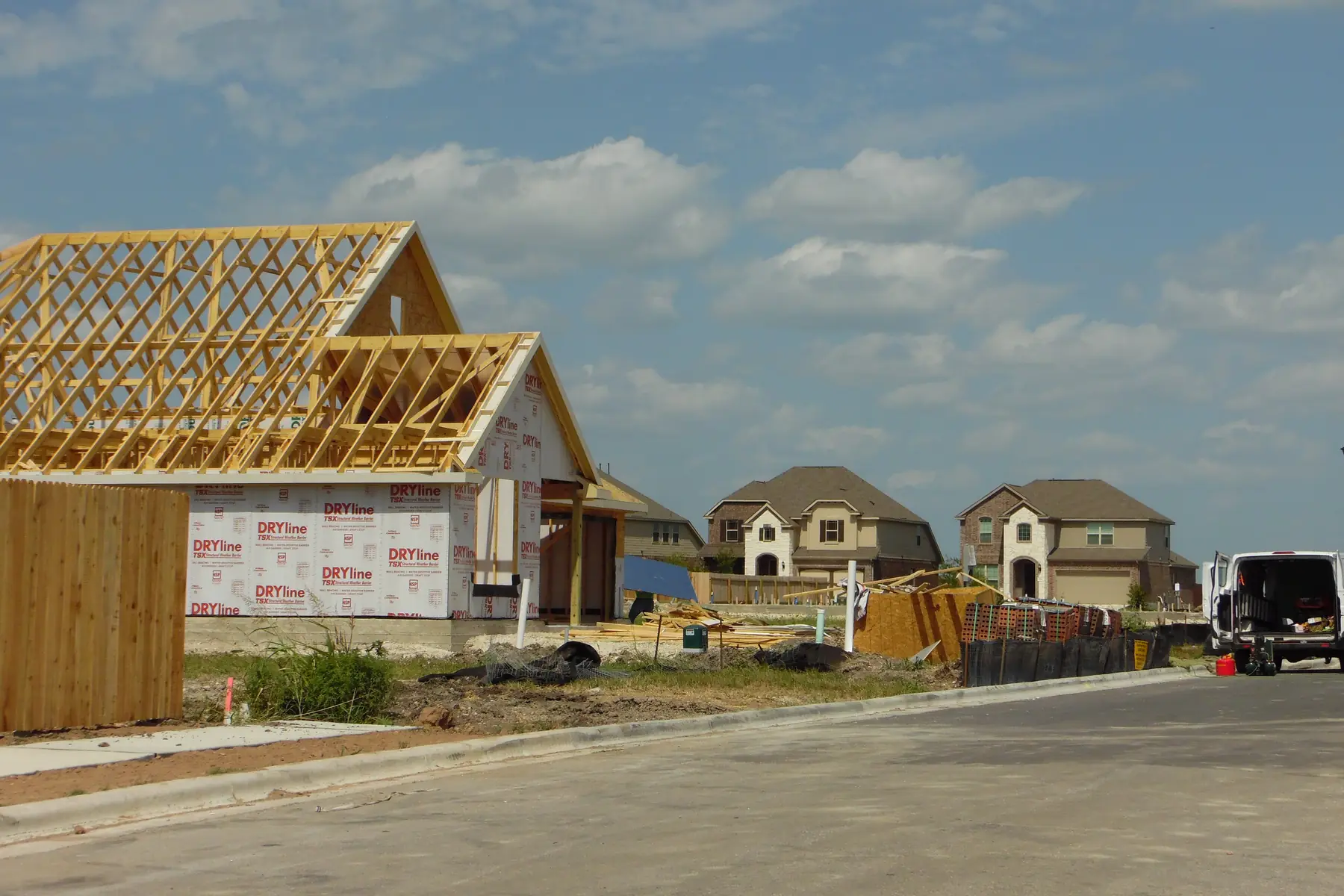 New homes under construction in a Pflugerville, Texas subdivision, roof trusses up and walls wrapped